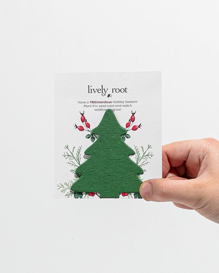 Lively Root holiday tree seed paper greeting card showing die-cut green tree shape with red berry botanical illustrations and "TREEmendous" message, plantable card that grows wildflowers after planting.