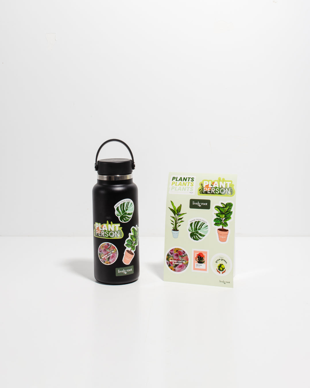 Black water bottle displayed alongside Lively Root plant sticker assortment showcasing various botanical designs and "Plant Person" messaging, decorative sticker set for plant enthusiast personalization and plant parent decor.